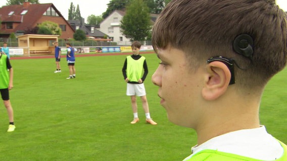 Ein Junge mit Hörgerät auf dem Fußballplatz. © Screenshot 