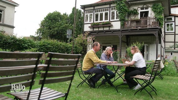 Weinhändlerin Hannah Bremer sitzt mit ihren Eltern im Garten an einem Tisch. © Screenshot 