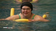 Eine Frau beim Schwimmkurs mit einer Schwimmnudel. © Screenshot 