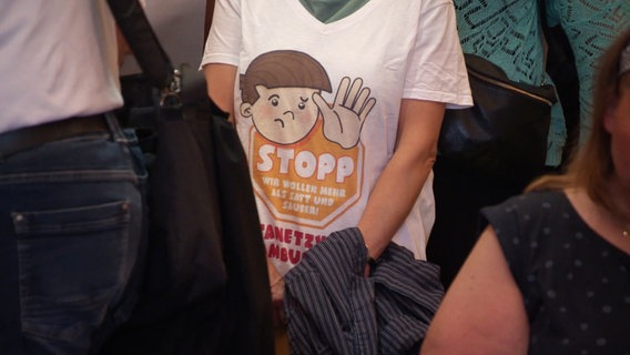 "Stopp - wir wollen mehr als satt und sauber" steht auf einem T-Shirt. © Screenshot 