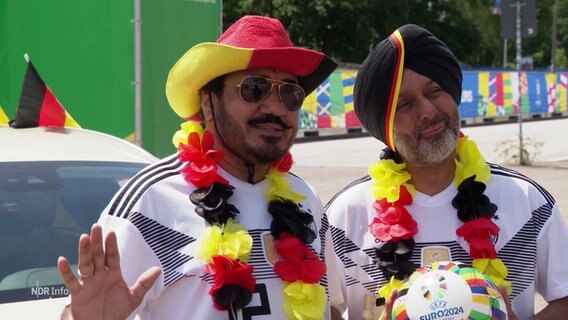 Zwei Männer mit Deutschlan-Fußballfan-Kleidung, der eine mit Hut, der andere mit Turban © Screenshot 