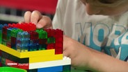 Ein Kind baut mit Legosteinen. © Screenshot 
