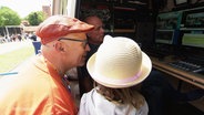 Ein Mann und ein Mädchen schauen in einen Übertragungswagen des NDR. © Screenshot 