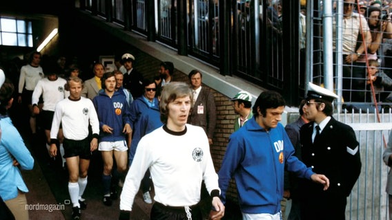 Die Fußball-National-Mannschaften der DDR und der BRD laufen nebeneinander im Stadion ein. © Screenshot 