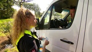 Eine Polizeibeamtin spricht mit dem Fahrer eines weißen Vans, der das Gelände des Hurricane-Festivals verlässt. © Screenshot 