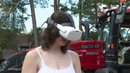 Eine junge Frau trägt eine weiße VR-Brille. © Screenshot 