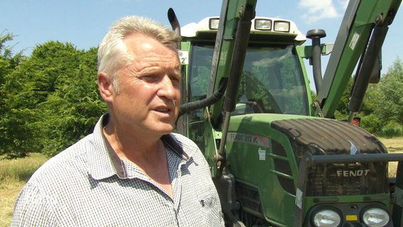 Ein Landwirt vor seinem Traktor spricht in die Kamera. © Screenshot 