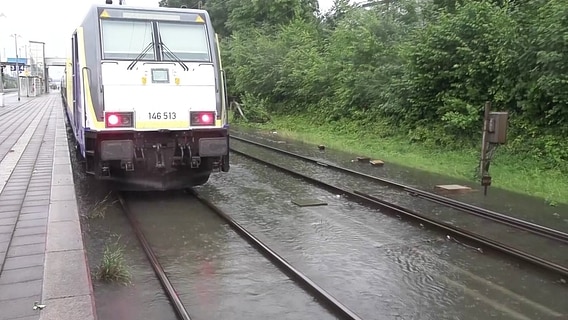 Ein Zug steht auf überschwemmten Gleisen. © Screenshot 