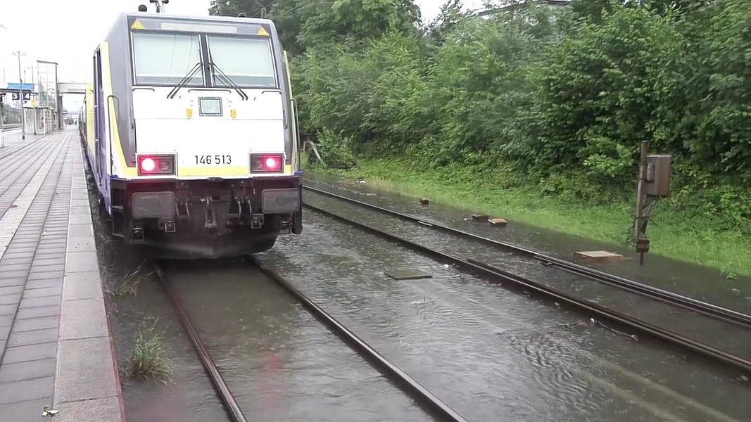 Ein Zug steht auf überschwemmten Gleisen.