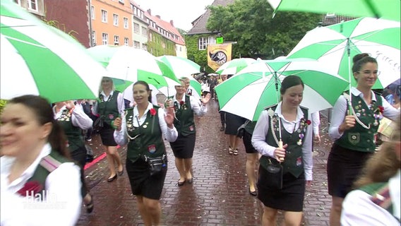 Teilnehmerinnen des Schützenumzugs ziehen mit Regenschirmen durch Hannover. © Screenshot 