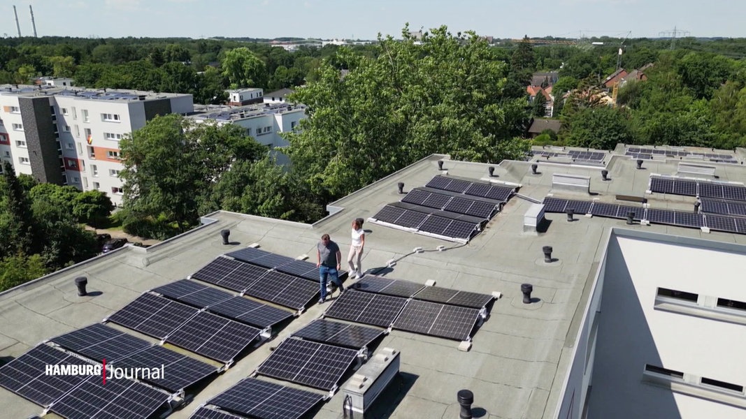 Zwei Menschen laufen über ein Dach, das mit Photovoltaik-Technik ausgestattet ist.