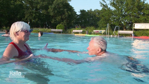 Eine Frau bringt einem Mann das Schwimmen bei. © Screenshot 