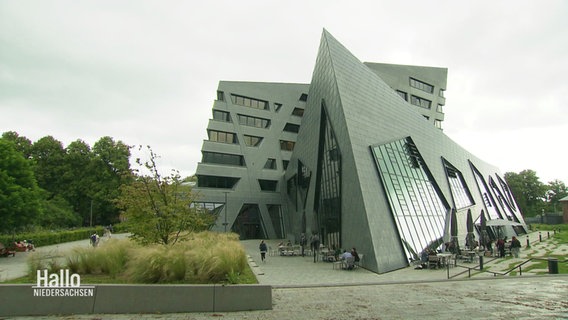 Gebäude der Leuphana Universität in Lüneburg. Es ist ein grauer, moderner und geometrische Bau mit vieol Glas und schrägen Winkeln. © Screenshot 