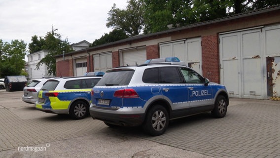 Zwei Polizeiautos und ein silbernes Auto stehen vor einer Garage. © Screenshot 