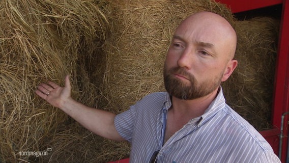 Ein Mann mit Glatze und Bart zeigt auf Bio-Brennstoff. © Screenshot 
