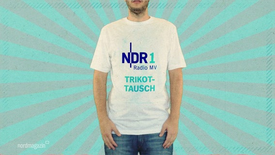 Ein Mann hat ein weißes T-Shirt an, auf dem in blauer Schrift "NDR 1 Radio MV Trikottausch" steht. © Screenshot 