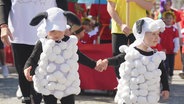 Zwei kleine Kinder, die als Schafe verkleidet sind, halten sich an den Händen. © Screenshot 