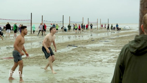Im regennassen Sand spielen Menschen Beachvolleyball. © Screenshot 