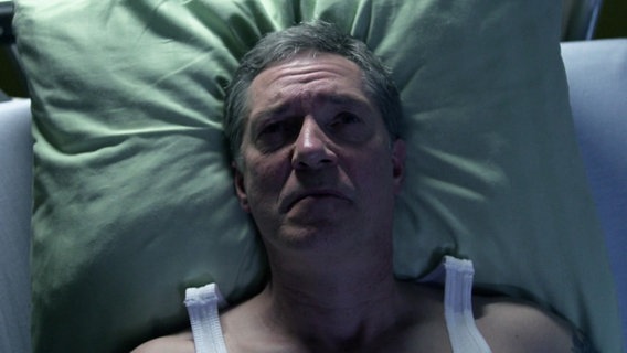 Ein Mann liegt in einem Bett. © Screenshot 