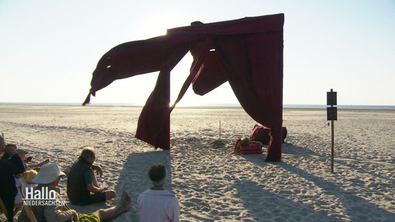 Ein Theatervorhang am Strand von Spiekeroog gibt Laiendarstellern eine Bühne. © Screenshot 