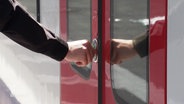 Eine Person betätigt den Öffnungsknopf einer Zugtür. © Screenshot 