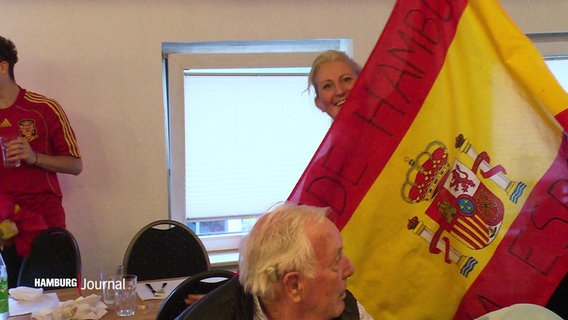 Eine Frau hält ein große spanische Flagge. © Screenshot 