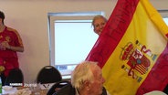 Eine Frau hält ein große spanische Flagge. © Screenshot 