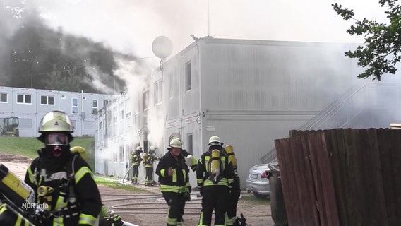 Feuerwehrleute löschen einen Brand in einem Containerwohnheim. © Screenshot 