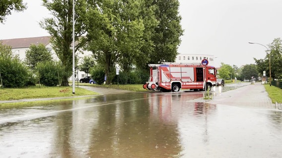 Ein Feuerwehrauto steht auf einer überfluteten Straße. © Screenshot 