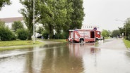 Ein Feuerwehrauto steht auf einer überfluteten Straße. © Screenshot 