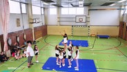 Cheerleader beim Training in einer Sporthalle. © Screenshot 