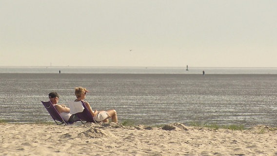 Zwei Urlauber am Strand blicken aufs Meer © Screenshot 