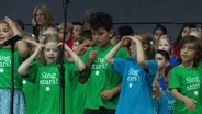 Grundschulkinder in "Singstar"-T-Shirts bei ihrem Bühnenauftritt © Screenshot 