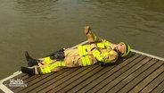 Ein Mann in Feuerwehrkleidung liegt erschöpft auf einem Steg an der Weser © Screenshot 