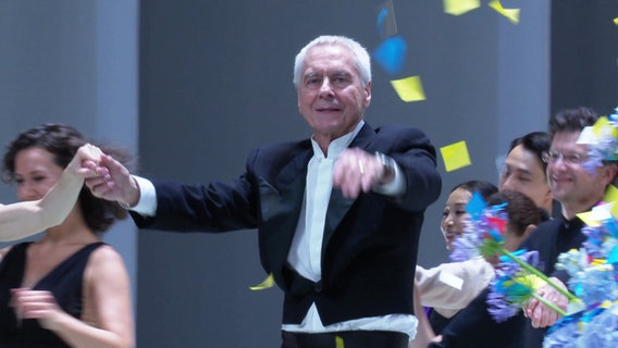 John Neumeier im Kreise seiner Tänzerinnen und Tänzer auf der Bühne der Hamburgischen Staatsoper. © Screenshot 