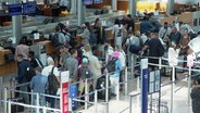 Reisende, darunter einige Familien, am Flughafenterminal. © Screenshot 