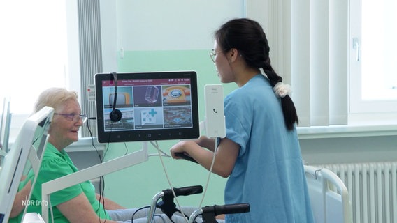 Pflegerin Thi Kim Dung Ngyuen spricht auf Station mit einer Patientin. © Screenshot 