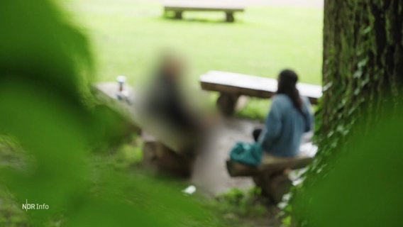 Eine Frau sitzt auf einer Parkbank, das Bild ist verschwommen. © Screenshot 
