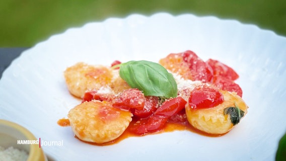 Auf einem Teller schön angerichtete Ravioli mit Tomate, Parmesan und Basilikum. © Screenshot 