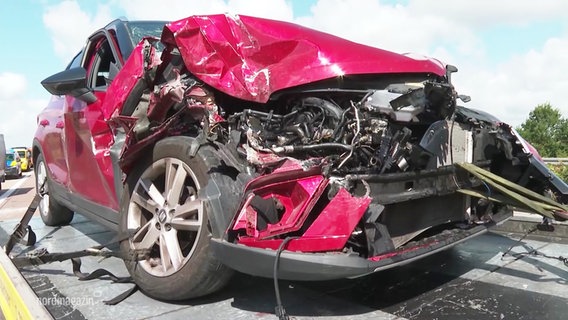Ein rotes Auto mit Totalschaden auf einem Abschleppfahrzeug. © Screenshot 