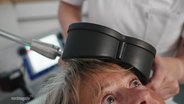 Eine Patientin wird mit einer Magnetspule am Kopf behandelt. © Screenshot 
