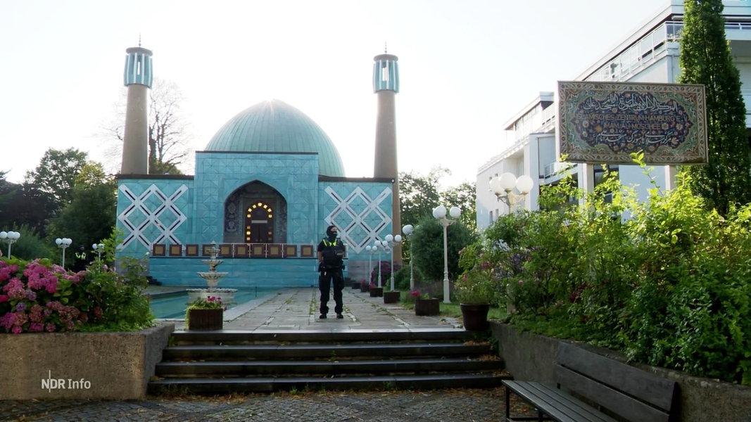 Eine Moschee mit zwei Minaretten, davor ein Polizist.