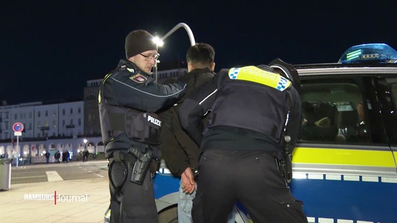 Zwei Polizisten nehmen einen jungen Mann in Gewahrsam. © Screenshot 