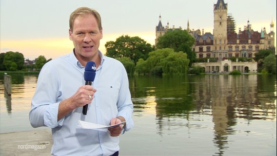 Thilo Tautz moderiert am Schweriner See. Hinter ihm ist das Schloss zu sehen. © Screenshot 