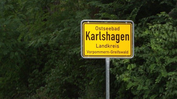 Vor einem Laubwald ist ein gelbes Ortseingangsschild, darauf ist Ostseebad Karlshagen zu lesen © Screenshot 