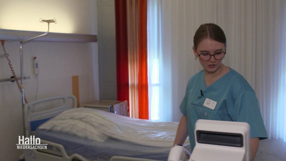 Die Pflege-Auszubildende Mattea Tälkers schaut auf Gerätschaften in einem Pflegezimmer. © Screenshot 