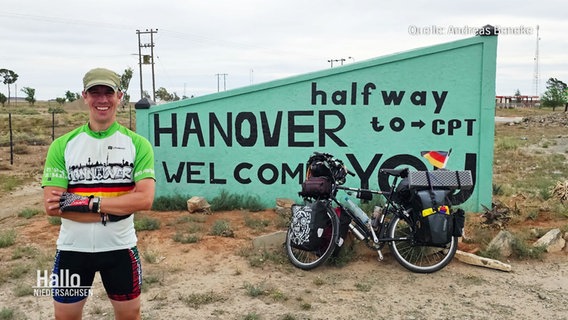 Radler Andreas Beneke posiert vor einem Schild mit der Aufschrift "Hanover Welcome". © Screenshot 