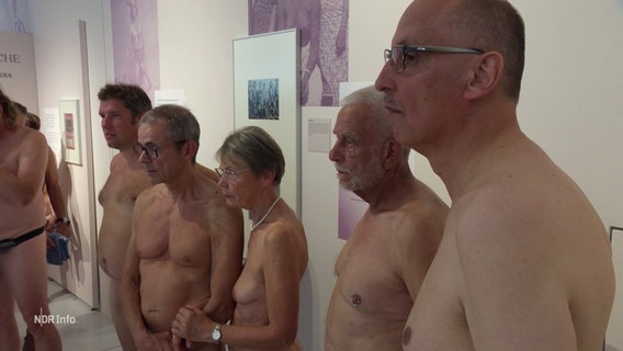 Nackte Menschen bei einer Führung in einer FKK-Ausstellung. © Screenshot 