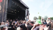 Die Wacken-Bühne mit den Firefighters zur Eröffnung. Davor feiernde Festival-Gäste. © Screenshot 