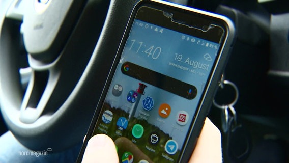 Am Steuer eines Autos hält eine Person ein Smartphone in der Hand. © Screenshot 